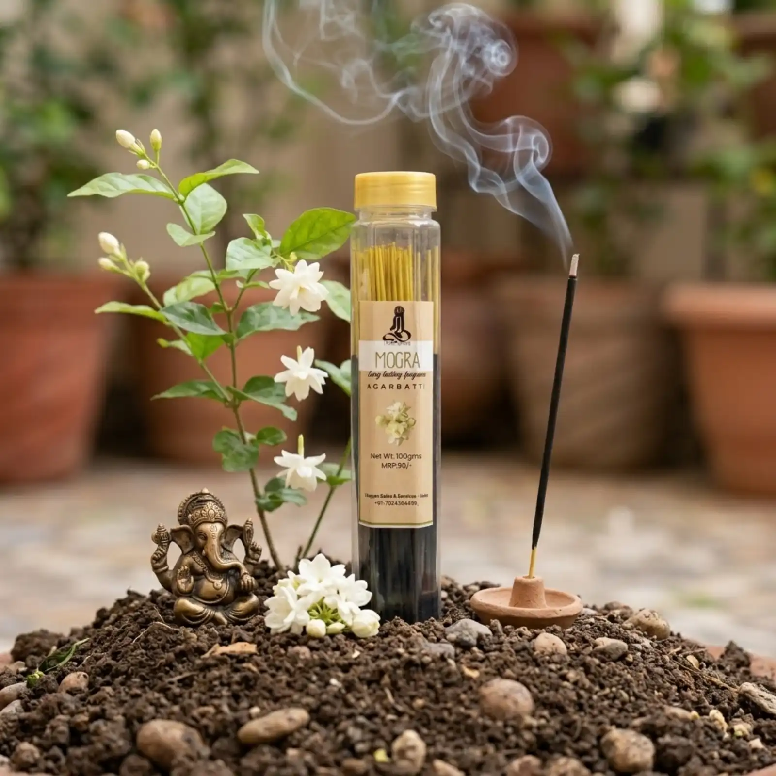 GURU Mogra Agarbatti container beside a fresh Mogra plant with white flowers